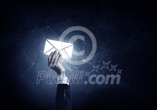 Businessman hand on dark background holding email glowing symbols Businessman hand on dark background holding email glowing symbols