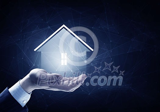 Hand of businessman on dark background showing glowing house sign Hand of businessman on dark background showing glowing house sign