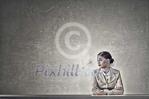 Young businesswoman sitting at table and looking away Young businesswoman sitting at table and looking away