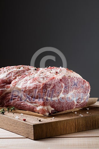 Photo of raw meat. Pork neck with herbs and green thyme on wooden board Photo of raw meat. Pork neck with herbs and green thyme on wooden board