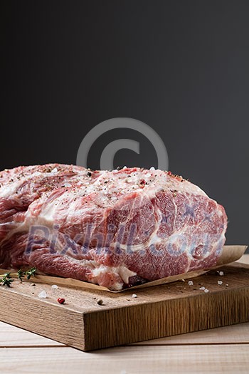 Photo of raw meat. Pork neck with herbs and green thyme on wooden board