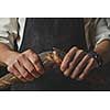 Men Hand breaking and separating a freshly baked baguette with poppy seeds on a dark background. Concept of bread.