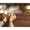 On a wooden brown table a cup of green tea in female hands