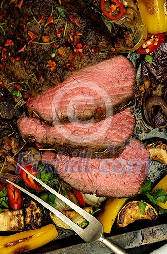 Sliced Grilled Beef rump steak on Baking tray with vegetables. Top view. Closeup. Sliced Grilled Beef rump steak on Baking tray with vegetables. Top view. Closeup.