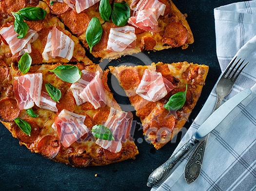 Homemade Pepperoni Pizza with fresh bacon over black background. Top view. Homemade Pepperoni Pizza with fresh bacon over black background. Top view.