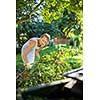 Pretty, young woman gardening in her garden, cutting branches, preparing the orchard for the winter