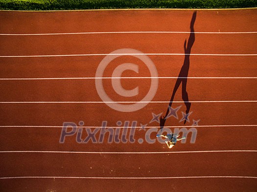 Shot of a young male athlete training on a race track. Sprinter running on athletics tracks seen from above Shot of a young male athlete training on a race track. Sprinter running on athletics tracks seen from above