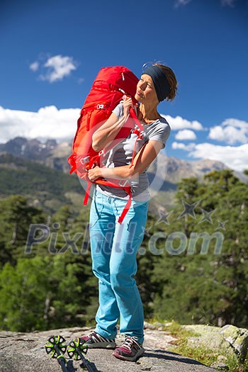 Pretty, female hiker in high mountains packing her backpack Pretty, female hiker in high mountains packing her backpack
