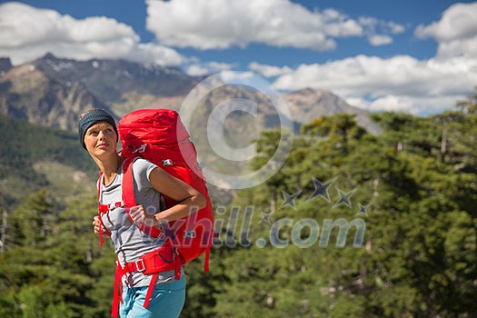 Pretty, female hiker in high mountains packing her backpack Pretty, female hiker in high mountains packing her backpack