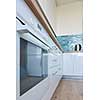 View to the bottom of the white kitchen with oven and brown floor