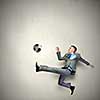 Businessman in suit hitting soccer ball in jump