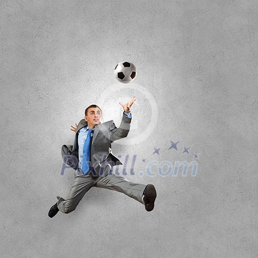 Businessman in suit catching soccer ball in jump Businessman in suit catching soccer ball in jump