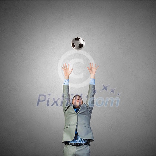 Businessman in suit catching soccer ball in jump Businessman in suit catching soccer ball in jump