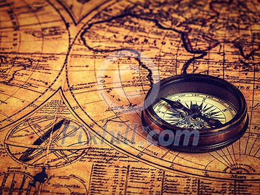 Travel geography navigation concept background - vintage retro effect filtered hipster style image of old vintage retro compass on ancient world map Travel geography navigation concept background - vintage retro effect filtered hipster style image of old vintage retro compass on ancient world map