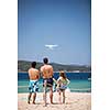 Young people flying a drone by remote control on a beach/sea shore, enjoying summer vacation.