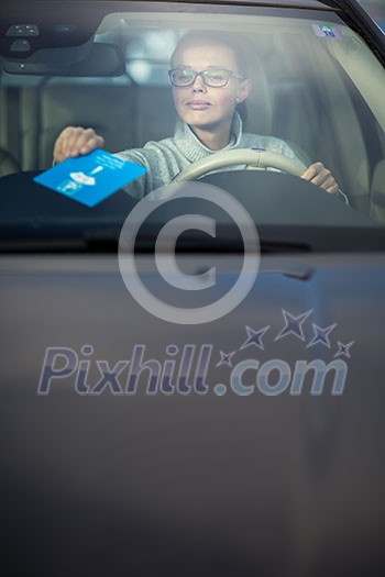 Pretty, young woman driving her new car - putting the necessary parking clock behind the windshield(color toned image; shallow DOF) Pretty, young woman driving her new car - putting the necessary parking clock behind the windshield(color toned image; shallow DOF)