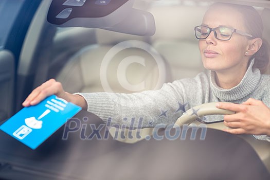 Pretty, young woman driving her new car - putting the necessary parking clock behind the windshield(color toned image; shallow DOF) Pretty, young woman driving her new car - putting the necessary parking clock behind the windshield(color toned image; shallow DOF)