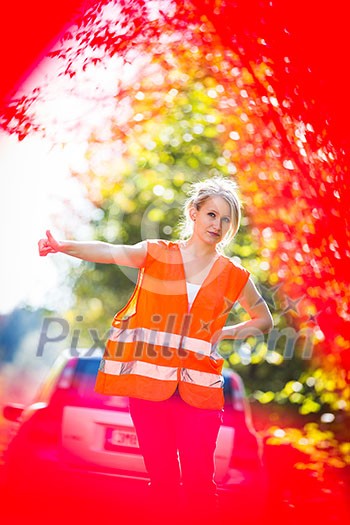 Young female driver wearing a high visibility vest on the roadside after her car has broken down Young female driver wearing a high visibility vest on the roadside after her car has broken down