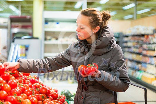 Beautiful, young woman shopping for fruits and vegetables in produce department of a grocery store/supermarket (shallow DOF; color toned image)