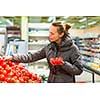 Beautiful, young woman shopping for fruits and vegetables in produce department of a grocery store/supermarket (shallow DOF; color toned image)