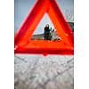 Realy angry young woman in a road distress situation - setting up a warning triangle and calling for assistance after her car broke down in the middle of nowhere on a freezing winter day