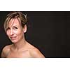 Portrait of a smiling middle aged caucasian woman against dark background - radiating confidence and feminity (shallow DOF; color toned image)
