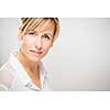 Portrait of a smiling middle aged caucasian woman against light grey background - radiating confidence and feminity (shallow DOF; color toned image)