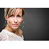 Portrait of a smiling middle aged caucasian woman against grey background (shallow DOF; color toned image)