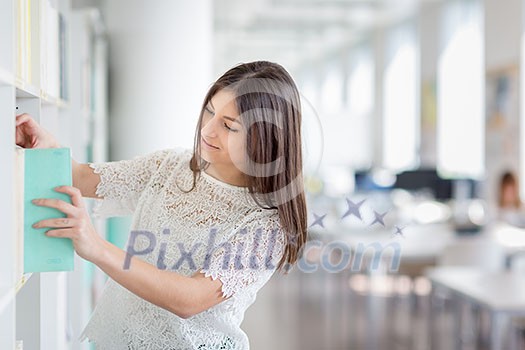 Pretty, young college student looking for a book in the library, studying for her exam Pretty, young college student looking for a book in the library, studying for her exam