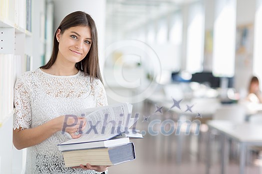 Pretty, young college student looking for a book in the library, studying for her exam Pretty, young college student looking for a book in the library, studying for her exam
