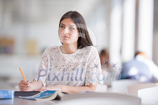 Pretty, young college student looking for a book in the library, studying for her exam Pretty, young college student looking for a book in the library, studying for her exam