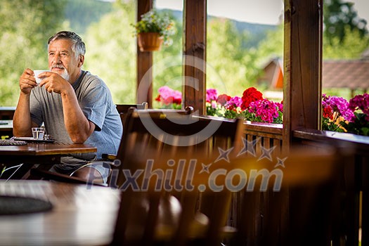 Handsome senior man enjoying his morning coffee on a mountain hotel terrace, while on vacation Handsome senior man enjoying his morning coffee on a mountain hotel terrace, while on vacation