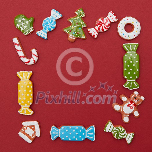 Frame of Christmas cookies of different shapes and colors on a red background Frame of Christmas cookies of different shapes and colors on a red background