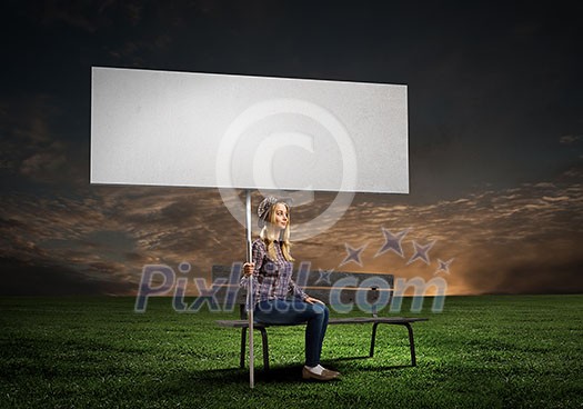 Young girl in casual with white banner sitting on bench. Place for text Young girl in casual with white banner sitting on bench. Place for text
