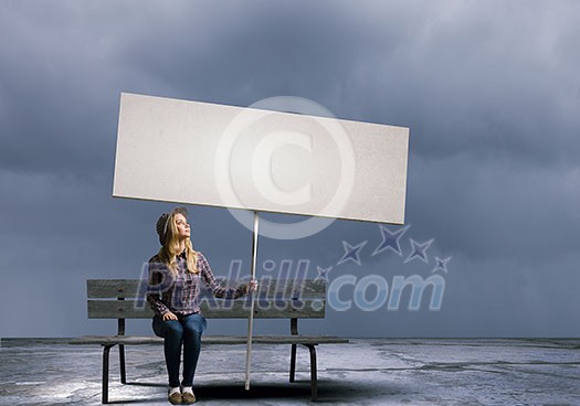 Young girl in casual with white banner sitting on bench. Place for text Young girl in casual with white banner sitting on bench. Place for text