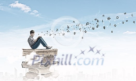 Teenager sitting on pile of books and reading Teenager sitting on pile of books and reading