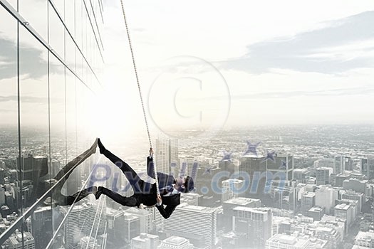 Concept of competition with businessman climbing office building with rope Concept of competition with businessman climbing office building with rope