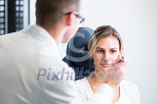 optometry concept - pretty young woman having her eyes examined by an eye doctor optometry concept - pretty young woman having her eyes examined by an eye doctor