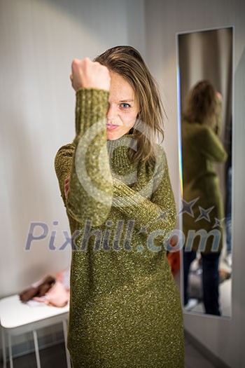 Young woman shopping happily in a fashion store, trying on some clothes she likes, disagreeing sometimes with her boyfriend's opinion (color toned image; shallow DOF) Young woman shopping happily in a fashion store, trying on some clothes she likes, disagreeing sometimes with her boyfriend's opinion (color toned image; shallow DOF)