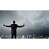 Back view of businessman in blue boxing gloves on city background