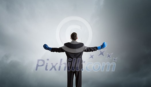 Back view of businessman in blue boxing gloves on city background Back view of businessman in blue boxing gloves on city background