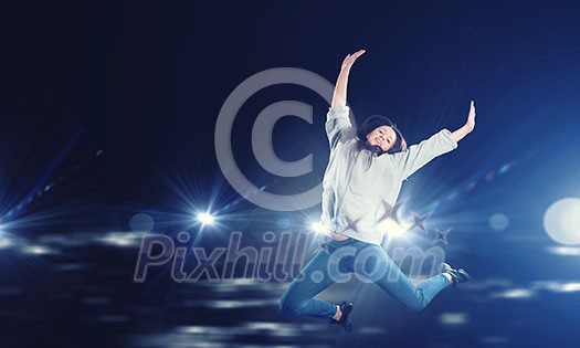 Young woman dancer jumping in spotlights on dark background Young woman dancer jumping in spotlights on dark background