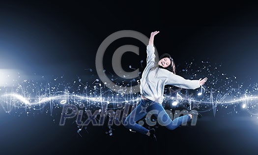 Young woman dancer jumping in spotlights on dark background Young woman dancer jumping in spotlights on dark background