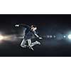 Modern style male dancer jumping in lights of spotlight