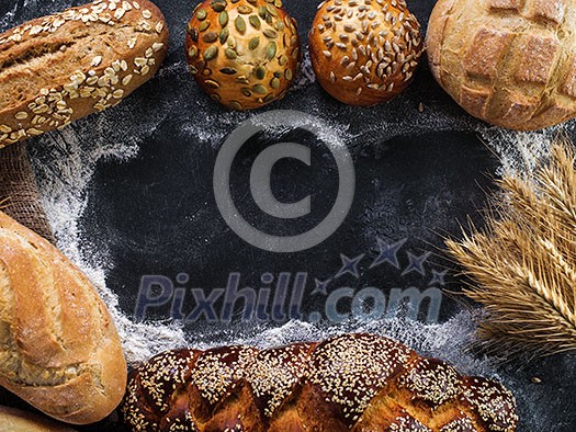 Assortment of fresh bread on the dark table. Copyspace for text. Assortment of fresh bread on the dark table. Copyspace for text.