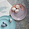 homemade easter eggs on a plate with rose petals on a stone background flat lay