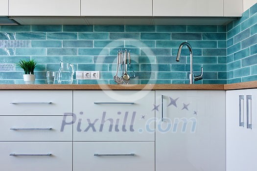 A cozy interior of a white kitchen with a blue tile A cozy interior of a white kitchen with a blue tile