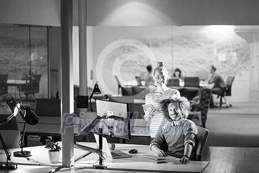 Two young designers are working on a new project in the night office using modern technology Two young designers are working on a new project in the night office using modern technology