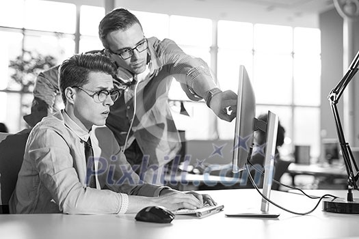 two business people using computer preparing for next meeting and discussing ideas with colleagues in the background two business people using computer preparing for next meeting and discussing ideas with colleagues in the background