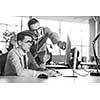 two business people using computer preparing for next meeting and discussing ideas with colleagues in the background